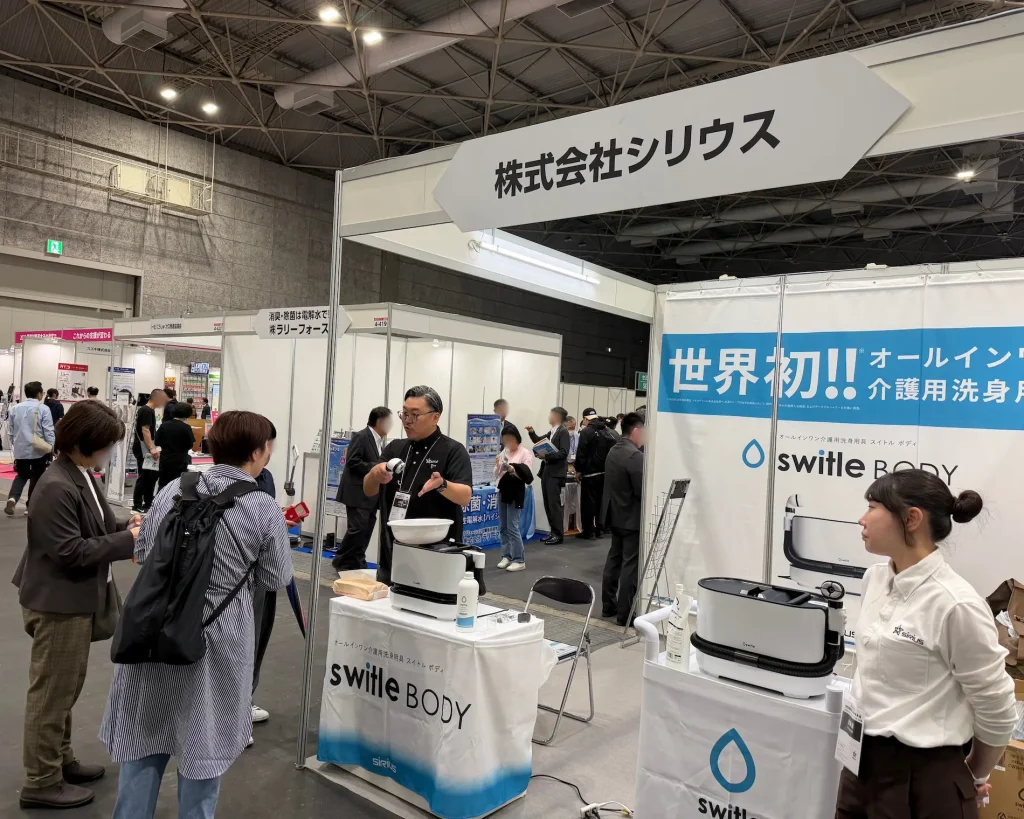 バリアフリー展2026の出展ブース。ベッド上で洗身可能な介護用洗浄製品のデモンストレーション。入浴機会の確保と介助者の負担軽減を両立する新技術。